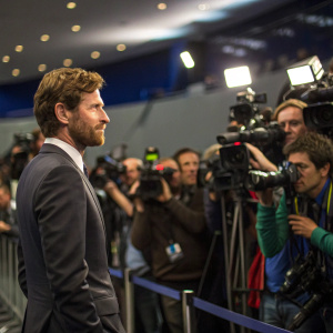 Andre Villas-Boas, wearing a tailored suit, stands at a press conference. Surrounded by journalists and photographers.