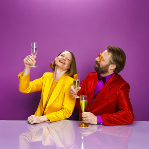 Jodie Foster and Randy Stone, sitting at a bar. Celebrating at the Academy Awards party. Both in formal attire, holding champagne flutes.