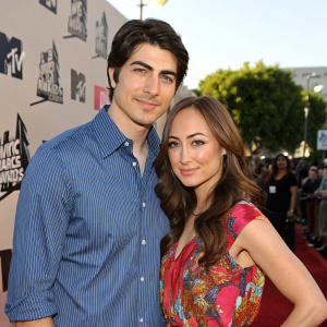 Brandon Routh and Courtney Ford at the MTV Movie Awards. They are dressed casually, Brandon in a blue striped shirt and Courtney in a vibrant floral top. They pose for a candid picture at the event.