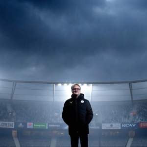 Claudio Ranieri, wearing a Puma jacket and glasses, posing in front of a stadium with cheering fans and colorful banners. The backdrop features logos from various sponsors including Mastercard, Lays, Nissan, Sony, and UniCredit.