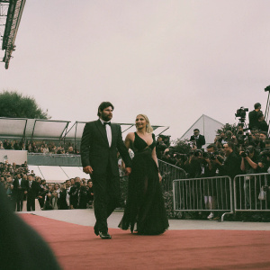 Karl Urban and Katee Sackhoff attending the Golden Lion Film Festival. Both dressed in formal attire, walking on red carpet. Festive ambiance, paparazzi capturing the moment.