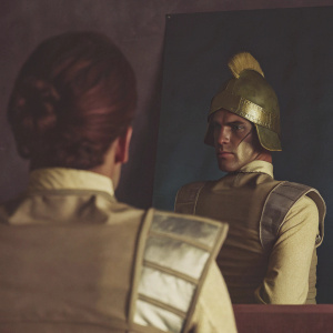 Mojo Jojo, from Powerpuff Girls, back view. Dressed in brown and metallic armor. Unique hairstyle and helmet. Dark blue backdrop.