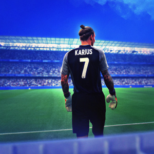 Loris Karius, the dedicated goalkeeper, stands on the sidelines of a packed stadium. His dark hair is styled in a high bun, and his arms are adorned with intricate tattoos. Dressed in a black and white soccer jersey featuring his name 'Karius' and the number '7', he gazes intently at the field ahead. The backdrop is a sea of cheering fans, blurred into a mosaic of excitement.