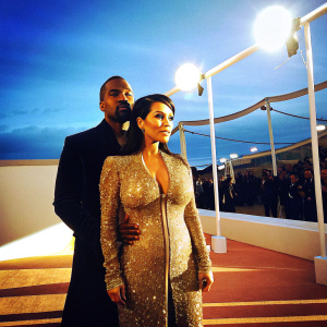 Kanye West and Kim Kardashian at the Grammy Awards. Kanye wearing a black suit, Kim in a golden sequined dress.