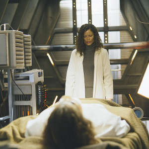 Salli Richardson-Whitfield as Allison Blake in a tense scene from Eureka. Sci-fi set with complex machinery and futuristic props in the background.