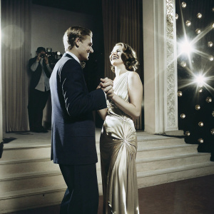 Peter O'Brien and Miranda Otto at an awards show. Both dressed in elegant attire. Peter in a navy suit, Miranda in a flowing gold dress. They share a smile on the stage with glitzy decorations and flashing cameras