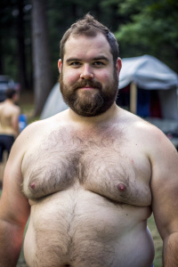 A fat hairy young man, with dark short beard and crew cut hair, completely bare, in a naturist camp