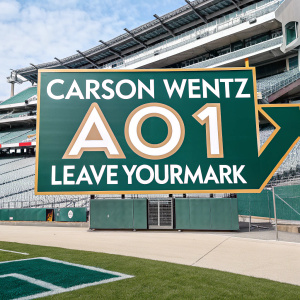 Carson Wentz AO1 Foundation's logo prominently displayed at a stadium. The design features an upward-pointing arrow and the slogan '#AO1LEAVEYOURMARK'