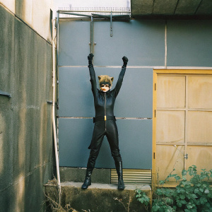 Digital illustration of Cat Noir, hero from Miraculous Ladybug. Playful pose, black outfit, against a cool blue backdrop.