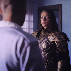 Maiev ShadowSong stands, her expression stern and unwavering. She wears ornate golden armor. The scene is illuminated by soft, warm lighting, casting gentle shadows around her.