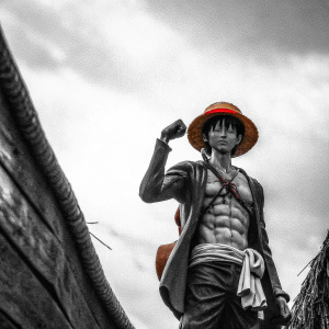 Render of Luffy from One Piece. Muscular body, straw hat, unique outfit, vibrant colors against grey backdrop.