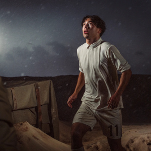 Shinji Okazaki, standing tall in his white SD Huesca uniform, number 11 on his shorts. Captured mid-stride against a desolate, snowy landscape, under a grey, somber sky. High-resolution, dramatic portrait