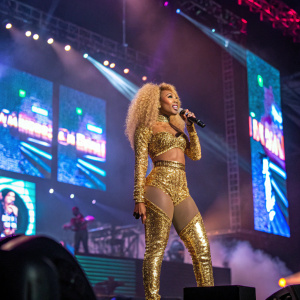 Nicki Minaj on stage performing at Coachella. Wearing a sparkling gold outfit, surrounded by LED screens.
