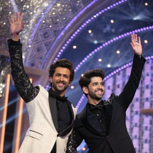 Hrithik Roshan and Rohit Saraf attend a glamorous award ceremony. They are grinning and waving to the audience. Lavish stage backdrop