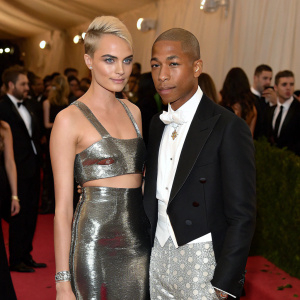 Cara Delevingne and Pharrell Williams attending the Met Gala. Delevingne in a metallic silver halter dress, Williams in a custom tuxedo.