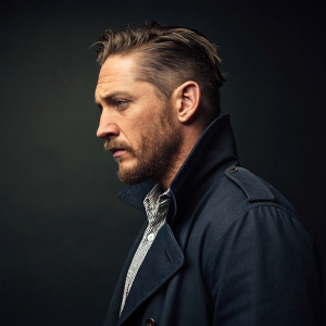 Tom Hardy, intense stare, rugged look with stubble, styled haircut. Dark studio backdrop