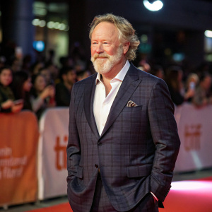 Timothy Busfield at the premiere event. Dapper suit, trimmed beard. Audience in the background