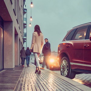 A red Bentley Bentayga W12 Signature SUV parked outside a bustling city street. Surrounded by people and city lights.
