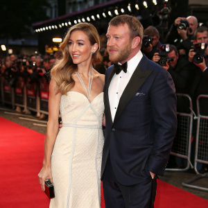 Jacqui Ainsley and Guy Ritchie attending a glamorous film festival. They are seen amidst a sea of flashing cameras and fans.