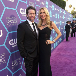 Reid Drescher and Aviva Drescher on a glamorous purple carpet at the annual Hollywood Awards. Both are elegantly dressed in formal attire. Colorful backdrop featuring various logos and symbols.