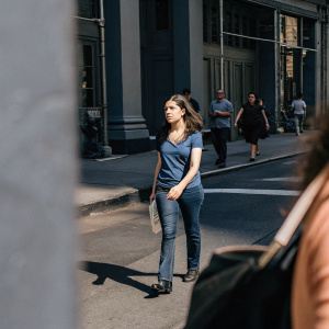 Anna Kendrick in a casual outfit, wearing a blue t-shirt and jeans, walking down a busy street in New York City.