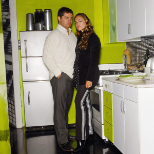 Matt LeBlanc as Joey Tribbiani and Drea de Matteo as Gina Tribbiani in a cozy New York apartment. Modern kitchen setup with various decorations