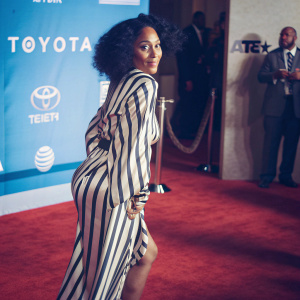 Tracee Ellis Ross in a stunning black and white striped dress, on the red carpet at the BET Awards. Behind her, the backdrop is splashed with the logos of major sponsors including Toyota and AT&T.