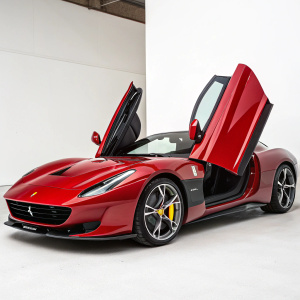 Red Ferrari Monza SP2, featuring black accents and logos. Displayed on a simple white background. Open doors reveal luxurious interior