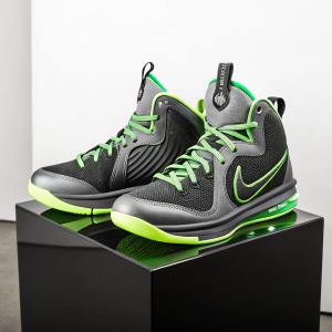 LeBron 9 Dunkman basketball shoes showcased on a sleek black display. Green accents and vibrant midsole. Textured upper and clear packaging visible. Sporty setup