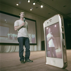 Mark Zuckerberg, in casual attire, presenting at an Apple event. iPhones and iPads displayed behind him.