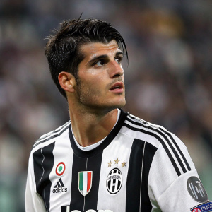Alvaro Morata, Spanish soccer player, wearing Juventus jersey with Adidas and sponsors logos. Intense look. Dark hair. Blurred background of stadium crowd.