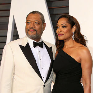 Laurence Fishburne and Gina Torres, elegantly dressed, at the Academy Awards afterparty. White backdrop