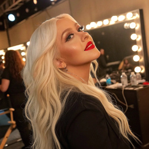 Christina Aguilera, with long platinum blonde hair and bright red lips, in a candid backstage shot.