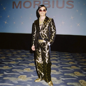Jared Leto in leopard print ensemble at award show. Shiny gold accessories, 'MORBIUS' backdrop