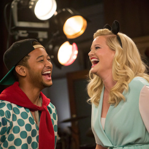 Tahj Mowry and Melissa Peterman on set of Baby Daddy. Laughing between takes. Studio lights in background.