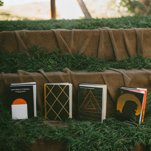 Various editions of 'A Clockwork Orange' book covers arranged in an artistic display. Different sizes and designs contrast against simple white backdrop.