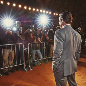 Matt Letscher, in a gray suit, at the bustling Hollywood premiere of 'Narcos: Mexico'. Bright lights and paparazzi capture the moment.