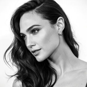 Gal Gadot in a stunning black and white portrait. Her long dark hair frames her face. The background is plain white. Artist's signature at the bottom.
