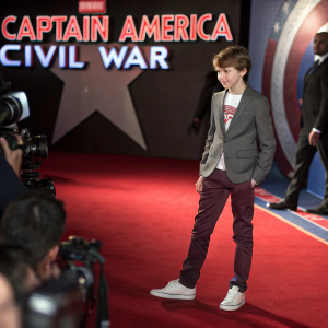 Ty Simpkins, young actor, at a Hollywood premiere. Stylized backdrop with 'Captain America Civil War' in bold letters. Red carpet with flashing cameras.