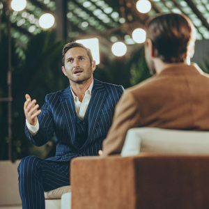 Frank Lampard in a dynamic interview. Wearing a blue pinstripe suit. Bright studio lights, modern backdrop.