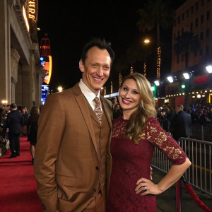 Steve Valentine, dressed in brown suit, and Shari, in a maroon lace dress, posing for a photo at the Egyptian Theatre premiere of 'CQ'. Hollywood's bustling night scene in the background.