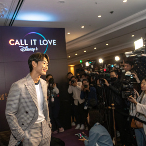 Kim Young-Kwang, at a bustling press conference, promoting 'Call It Love' on Disney+. The room is filled with flashing cameras and reporters.