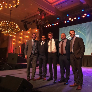 At the glitzy gala of the 3rd Annual Shorty Social Good Awards, a gathering of gentlemen strike a relaxed pose on stage. The room, a sea of warm, inviting lights and cheerful chatter, exudes an atmosphere of unity and celebration.