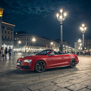 A stunning red Audi RS5 convertible parked in a bustling city square. Bright streetlights and lively crowd in the background.