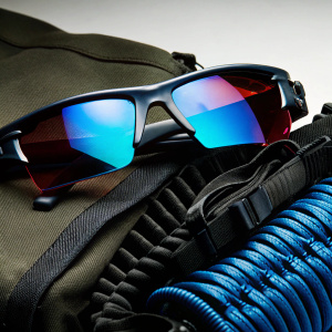 Product photo of Oakley Men's Flak 2.0 XL Sunglasses. Sleek, modern design. Black frame with bold, reflective lens changing from reddish to purplish. Durable, flexible material. Black temples. White background.