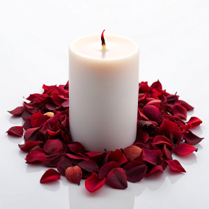 white candle in the middle, dry red rose leaves around the candle, clean rouge red box aside