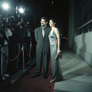 David Mamet and Rebecca Pidgeon on a glamorous red carpet. Flashing cameras and paparazzi surround them.