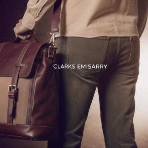 Realistic digital artwork showcasing a Clarks Emisarry bag alongside a casual male figure. The illustration highlights the bag's rich brown hues, intricate leather details, and distinctive design. 'Clarks Emisarry' text prominently displayed. Set against a serene, neutral background.