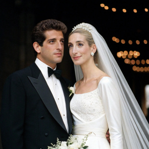 Formal wedding portrait of John F. Kennedy Jr. and Carolyn Bessette Kennedy. Dark backdrop with faint lights