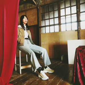 Dea Artika, Asian model, wearing casual outfit. She is sitting in a minimalist studio with white walls and simple decor.